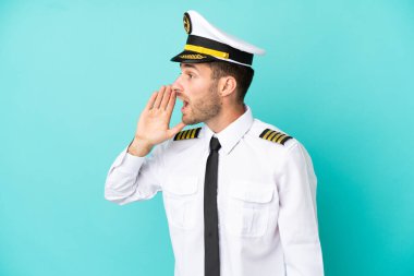 Kafkasyalı uçak pilotu mavi arka planda izole edilmiş ve ağzı sonuna kadar açık bağırıyor.