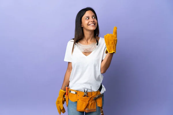 Jovem Eletricista Mulher Isolada Fundo Roxo Apontando Para Uma Grande — Fotografia de Stock