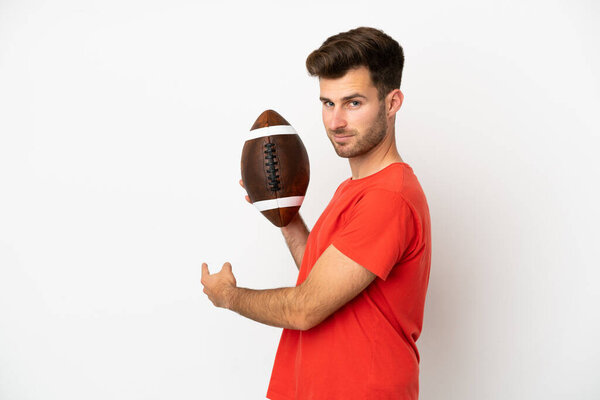 Young caucasian man playing rugby isolated on white background pointing back