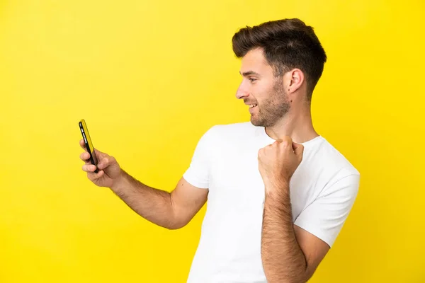 Joven Hombre Guapo Caucásico Aislado Sobre Fondo Amarillo Usando Teléfono —  Fotos de Stock