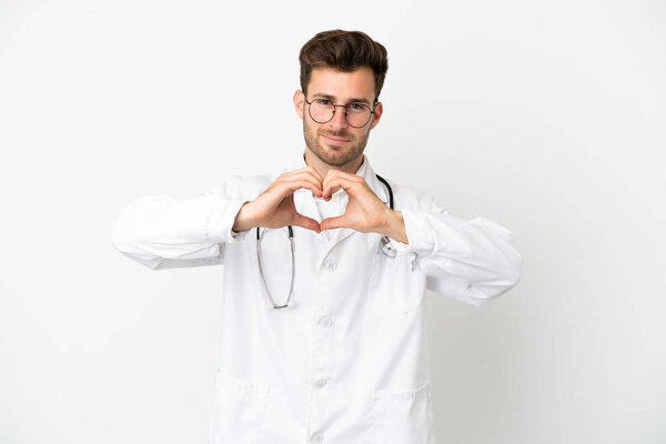 Young doctor caucasian man over isolated on white background wearing a doctor gown making a heart with hands