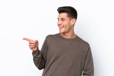 Beyaz bakkalda izole edilmiş genç, yakışıklı beyaz bir adam. Parmakla göstererek bir ürün sunuyor.