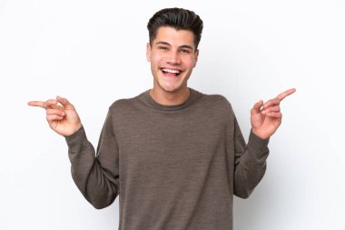 Beyaz bakkalda izole edilmiş beyaz, yakışıklı beyaz bir adam parmak uçlarını gösteriyor ve mutlu.