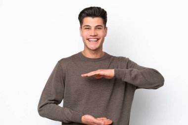 Beyaz fırında izole edilmiş yakışıklı beyaz bir adam. Avucunun içinde bir reklam koymak için hayali bir mekan tutuyor.