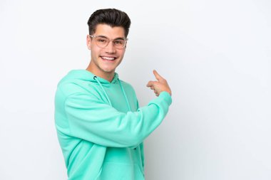 Beyaz fırında izole edilmiş yakışıklı beyaz adam geriye doğru işaret ediyor.