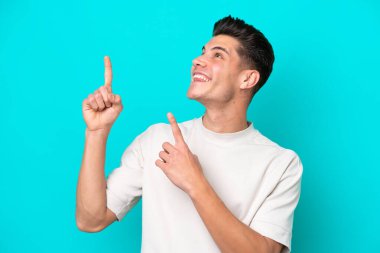 Genç, yakışıklı, beyaz bir adam mavi bir bakkalda izole edilmiş ve işaret parmağıyla işaret ediyor. Harika bir fikir.