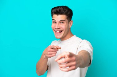 Genç, yakışıklı, beyaz bir adam mavi fırında izole edilmiş, şaşırmış ve ön tarafı işaret ediyor.