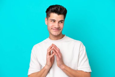 Genç, yakışıklı, beyaz bir adam, mavi bir fırında izole edilmiş bir şekilde bir şeyler çeviriyor.