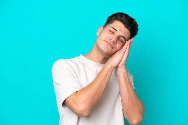 Genç, yakışıklı, beyaz bir adam mavi fırında tek başına uyku jesti yapıyor.