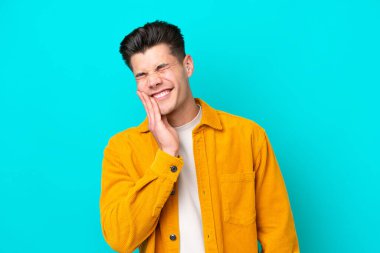 Genç, yakışıklı, beyaz bir adam mavi fırında diş ağrısı ile izole edilmiş.