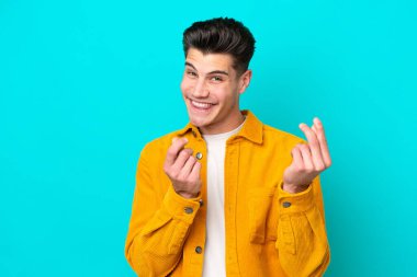 Genç, yakışıklı, beyaz bir adam mavi fırında izole edilmiş, para hareketi yapıyor.