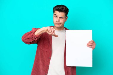 Genç, beyaz bir adam mavi bir bakkalda izole edilmiş, elinde boş bir levha var ve kötü sinyal veriyor.