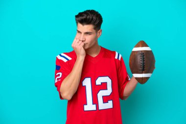 Rugby oynayan Kafkasyalı genç adam mavi arka planda izole edilmiş. Şüpheleri var.