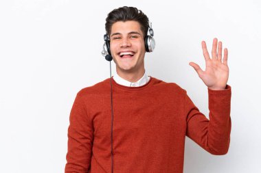 Tele pazarlamacı, beyaz arka planda izole edilmiş bir kulaklıkla çalışan beyaz bir adam mutlu bir ifadeyle selam veriyor.