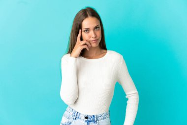 Soyutlanmış mavi arka planda genç bir kadın bir fikir düşünüyor.