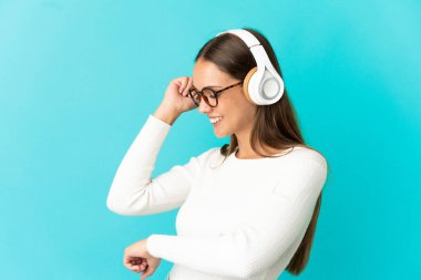Soyutlanmış mavi arka plan müzik ve dans dinleyen genç bir kadın.