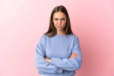 Soyutlanmış pembe arka planı olan genç bir kadın üzgün.