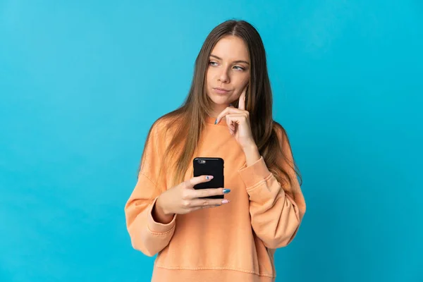 Νεαρή Λιθουανή Γυναίκα Απομονωμένη Μπλε Φόντο Χρησιμοποιώντας Κινητό Τηλέφωνο Και — Φωτογραφία Αρχείου