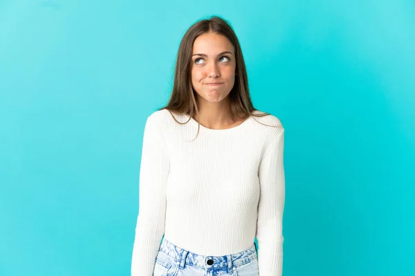 Ung Kvinna Över Isolerad Blå Bakgrund Med Tvivel När Tittar — Stockfoto