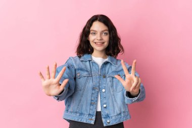 Pembe arka planda izole edilmiş genç Ukraynalı kız parmaklarıyla sekizi sayıyor.