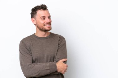 Beyaz arka planda izole edilmiş genç Brezilyalı adam yan tarafa bakıyor.