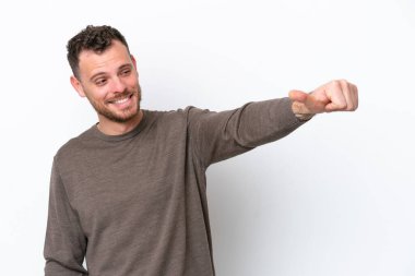 Beyaz arka planda izole edilmiş genç Brezilyalı bir adam baş parmak hareketi yapıyor.