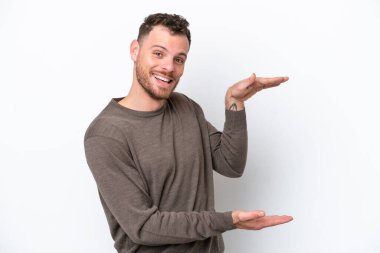 Beyaz arka planda izole edilmiş genç Brezilyalı bir adam bir ilan vermek için kopyalama alanı tutuyor