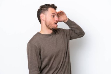 Genç Brezilyalı bir adam beyaz arka planda izole edilmiş. Sürpriz bir ifadeyle yan tarafa bakıyor.