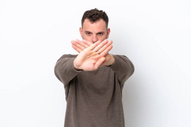 Genç Brezilyalı bir adam beyaz arka planda izole edilmiş bir şekilde bir eylemi durdurmak için el hareketi yapıyor.