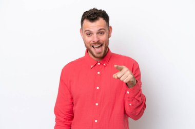 Beyaz arka planda izole edilmiş genç Brezilyalı adam şaşırmış ve ön tarafı işaret ediyor.