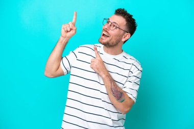 Mavi arka planda izole edilmiş genç Brezilyalı adam işaret parmağıyla işaret etmek harika bir fikir.
