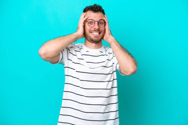 Mavi arka planda izole edilmiş genç Brezilyalı adam gergin hareketler yapıyor.