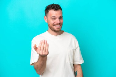 Genç Brezilyalı bir adam mavi arka planda izole edilmiş ve davet edilmişti. Gelmene sevindim.