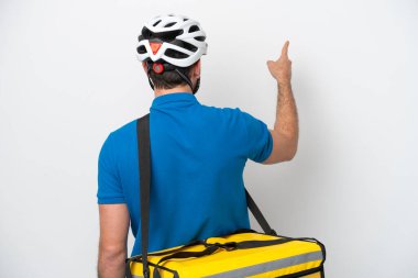 Beyaz arka planda izole edilmiş termal sırt çantalı genç Brezilyalı adam işaret parmağıyla işaret ediyor.