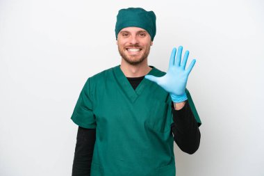 Cerrah Brezilyalı yeşil üniformalı adam beyaz arka planda izole edilmiş, parmaklarıyla beşi sayıyor.