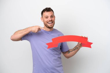 Genç Brezilyalı bir adam beyaz arka planda izole edilmiş, elinde boş bir levhayla onu işaret ediyor.