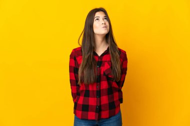 Genç Brezilyalı kız sarı arka planda izole edilmiş ve yukarı bakıyor.