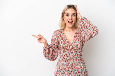 Beyaz arka planda izole edilmiş genç beyaz kadın şaşırmış ve işaret ediyor.