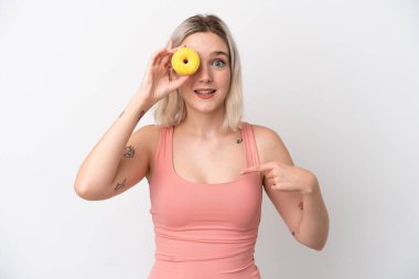 Beyaz arka planda izole edilmiş genç beyaz bir kadın elinde donut ve mutlu.