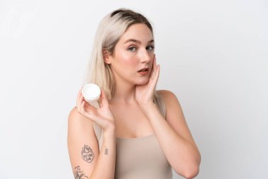 Beyaz arka planda nemlendirici ile izole edilmiş genç beyaz kadın.