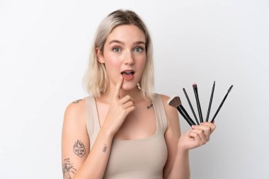 Beyaz arka planda izole edilmiş beyaz bir kadın elinde makyaj fırçası tutuyor.