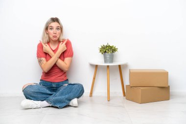 Genç bir kadın beyaz arka planda izole edilmiş kutuların arasına taşınıyor.