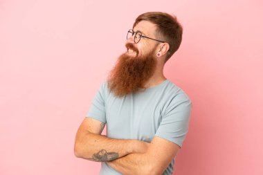 Pembe arka planda izole edilmiş genç, beyaz adam yan tarafa bakıyor.