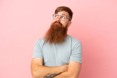 Pembe arka planda izole edilmiş genç, beyaz bir adam omuzlarını kaldırırken şüpheyle hareket ediyor.