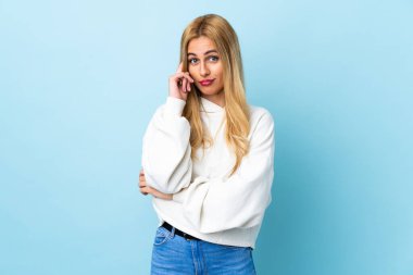 Genç Uruguaylı sarışın kadın izole edilmiş mavi arka planda bir fikir düşünüyor.