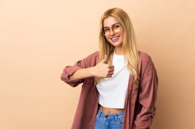 Genç Uruguaylı sarışın kadın, izole edilmiş geçmişinden dolayı baş parmak işareti yapıyor.