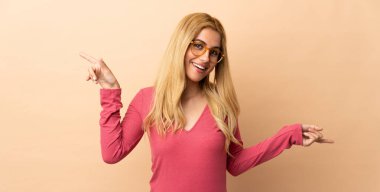 Genç Uruguaylı sarışın kadın izole edilmiş arka planda parmak ucunda ve mutlu.