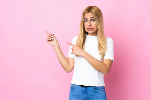 Joven Mujer Rubia Uruguaya Sobre Fondo Rosa Aislado Asustada Señalando —  Fotos de Stock