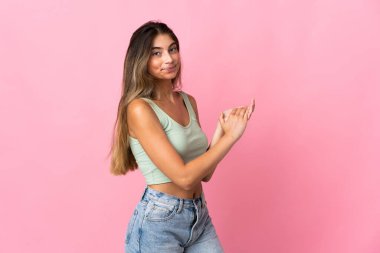 Pembe arka planda izole edilmiş genç beyaz kadın alkışlıyor.