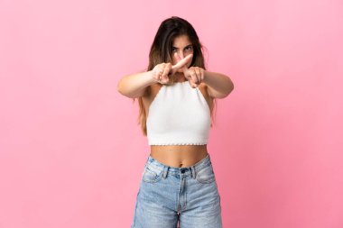 Pembe arka planda izole edilmiş genç beyaz kadın bir hareketi durdurmak için eliyle jest yapıyor.